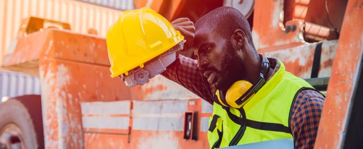 Construction worker wiping brow in exhaustion