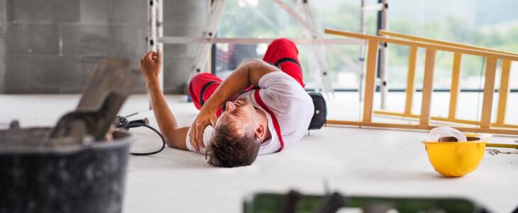 Construction worker laying on ground in pain.