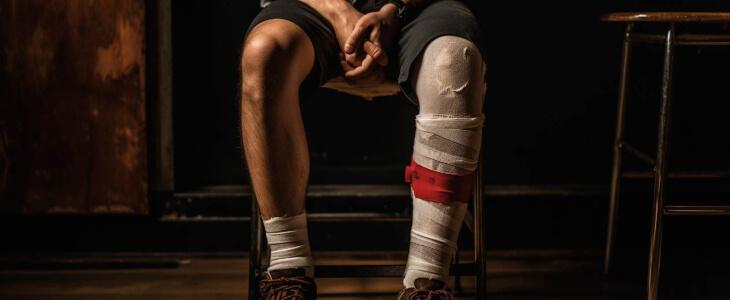 Man sitting with leg cast, depicting either work injury or disability.