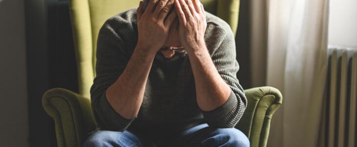 Sad middle aged man with hands on his head.
