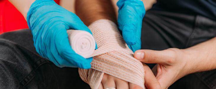 Medical worker wrapping bandage around hand of burn injury victim