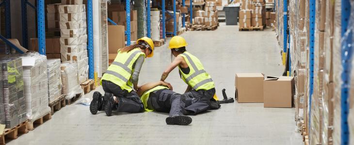 Warehouse workers gathering around coworker who is seriously injured.