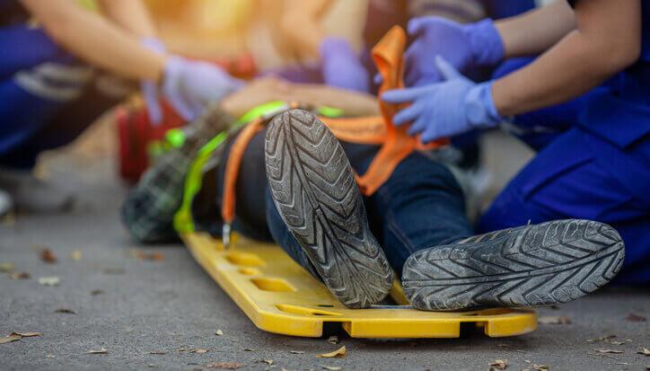 Injured worker laying on a stretcher with EMTs attending