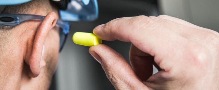 Construction worker putting in an ear plug.
