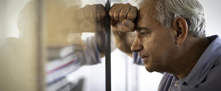 Man leaning on window after getting fired for workers' compensation claim.